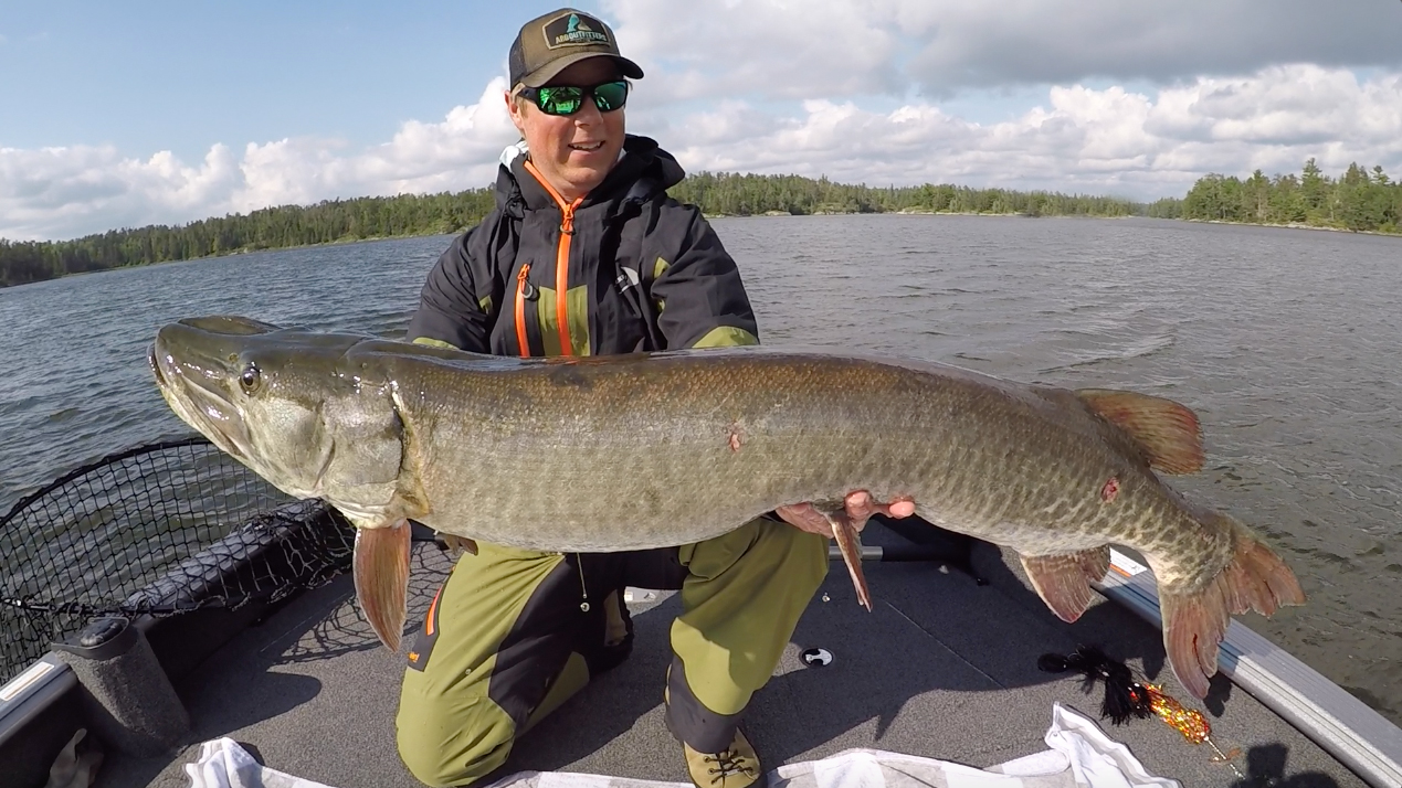 A man holding a large fish while out on a lake.