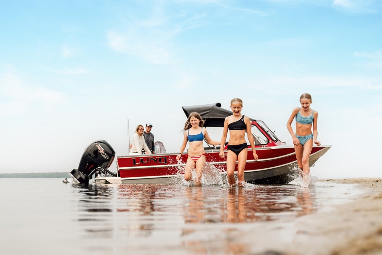 A family with their Lund boat beached while children walk on the beach