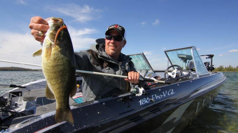 Fisherman Pulling Catch out of Lund Pro-V GL Dual Console Fishing Boat